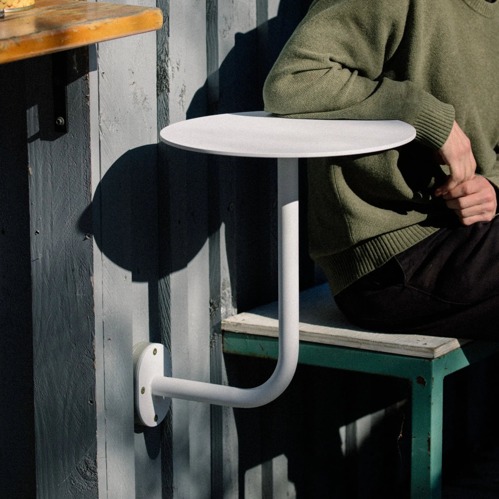 person sitting at a seat beside the wall mounted table bracket