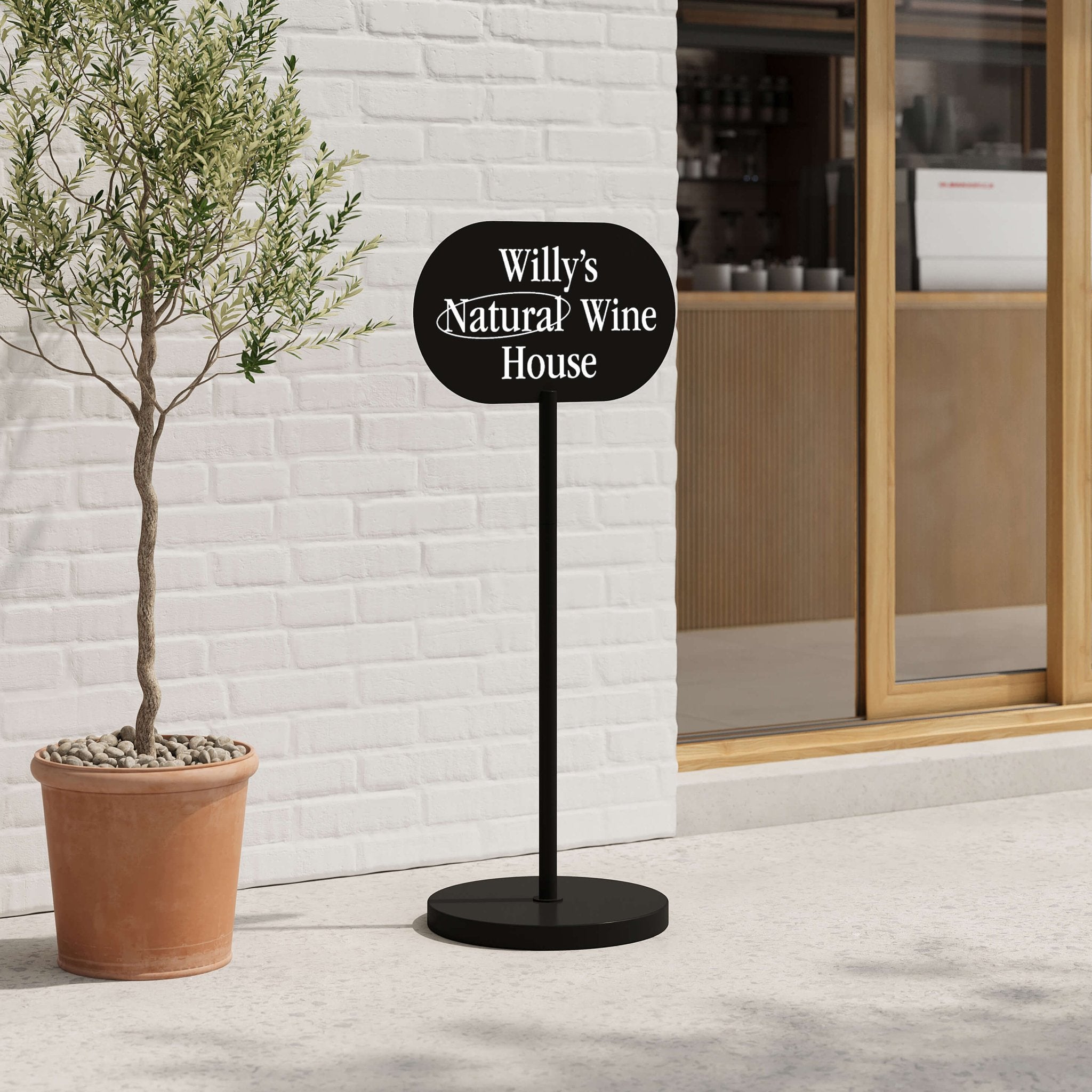 black wayfinding standing sign beside a tree in front of the store