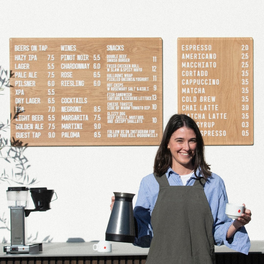 Two wooden peg letter boards in large and small in natural oak finish with café menu, woman standing beside display