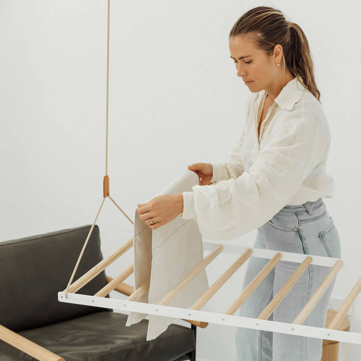 person hanging clothes on ceiling hanging drying rack