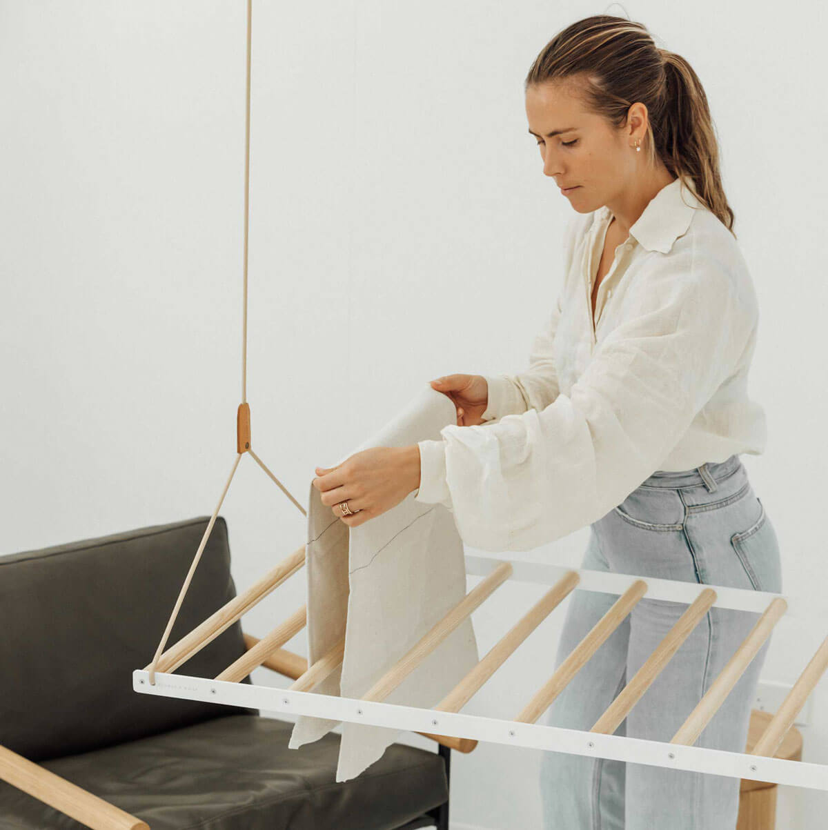 person hanging clothes on ceiling hanging drying rack