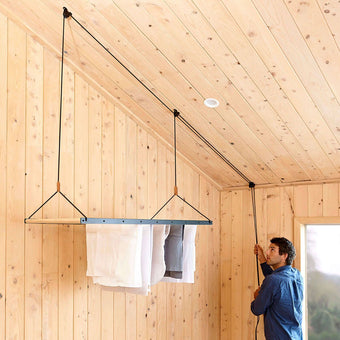 person pulling the rope to lift the ceiling hanging drying rack