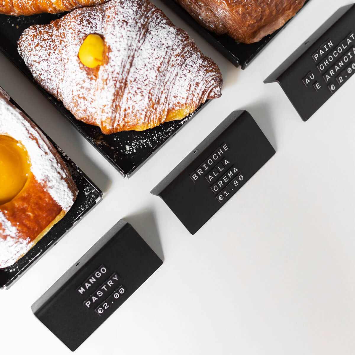 a birds eye view of three black signs in front of different pastries