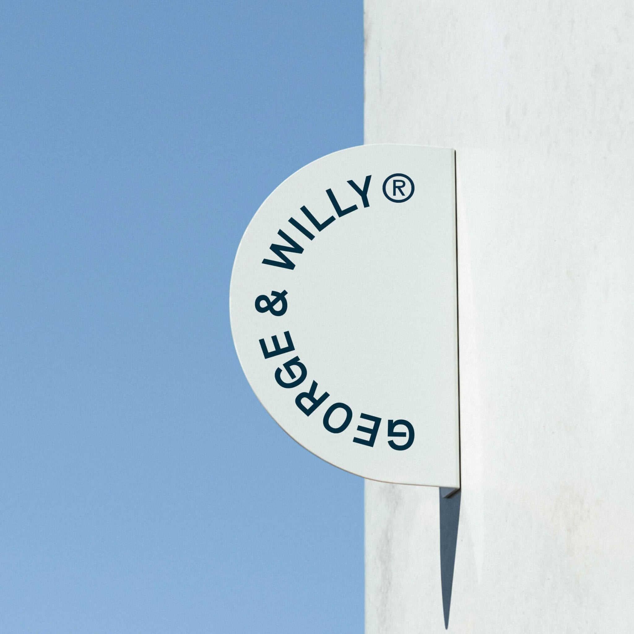 white half round blade sign installed on concrete wall with george & willy branding