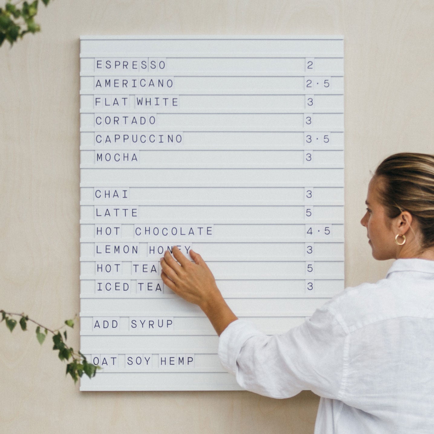 girl adjusting the letters on a white letter menu board showing coffee menu