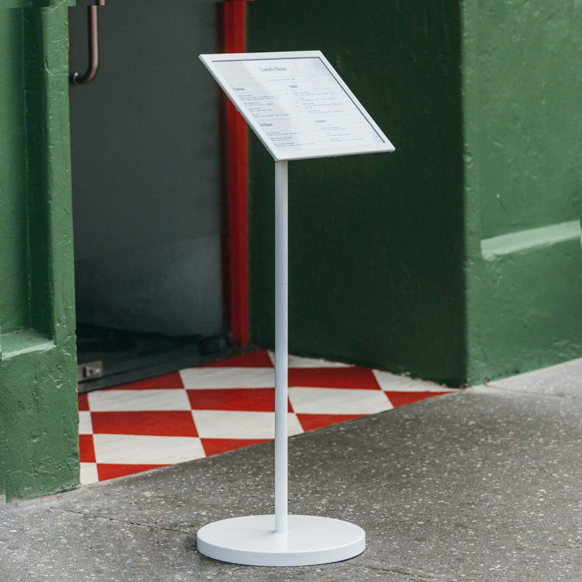 white menu stand in front of green restaurant facade