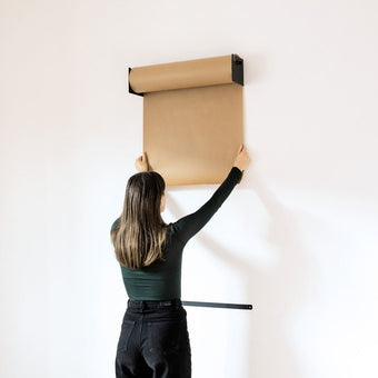 girl pulling down more kraft paper from the studio roller