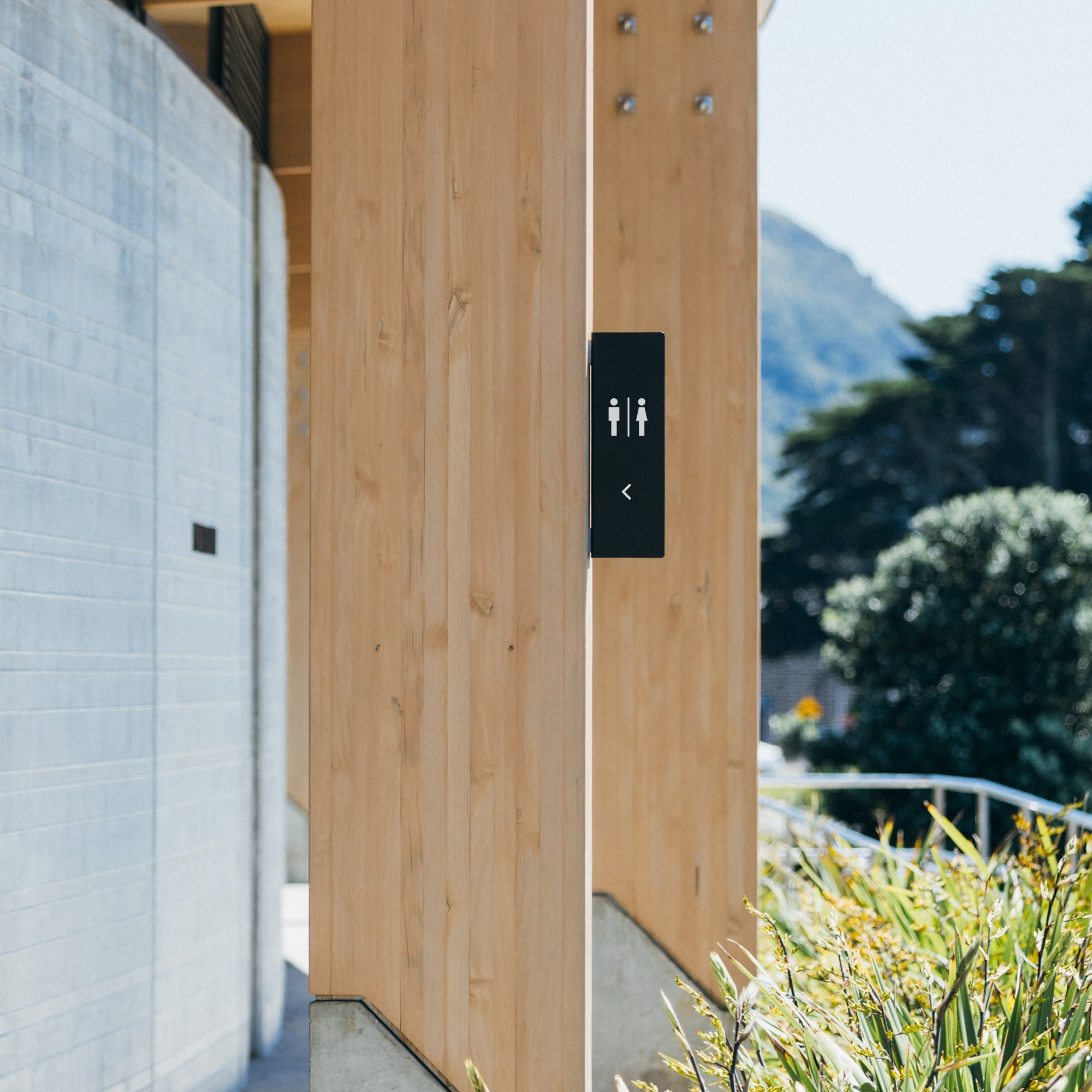 vertical blade wall restroom sign on a wooden wall