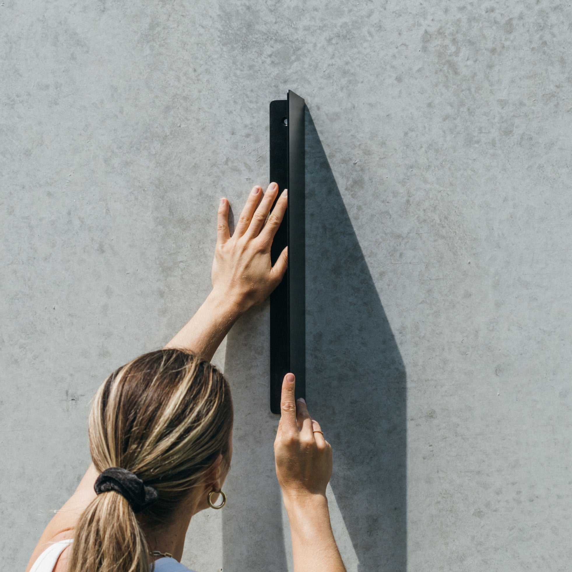 shot of the vertical metal blade sign to show the folded mounting panel and person putting it up on the wall