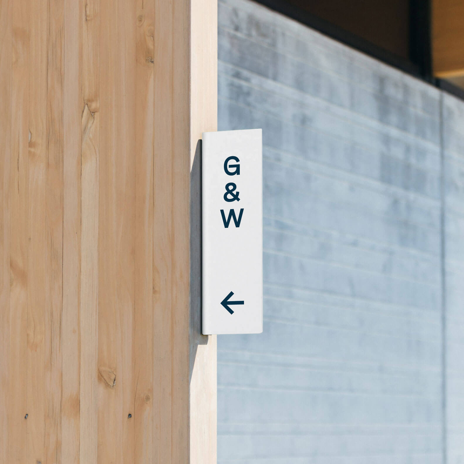 white vertical blade metal sign wall mounted on a wooden beam used as wayfinding sign