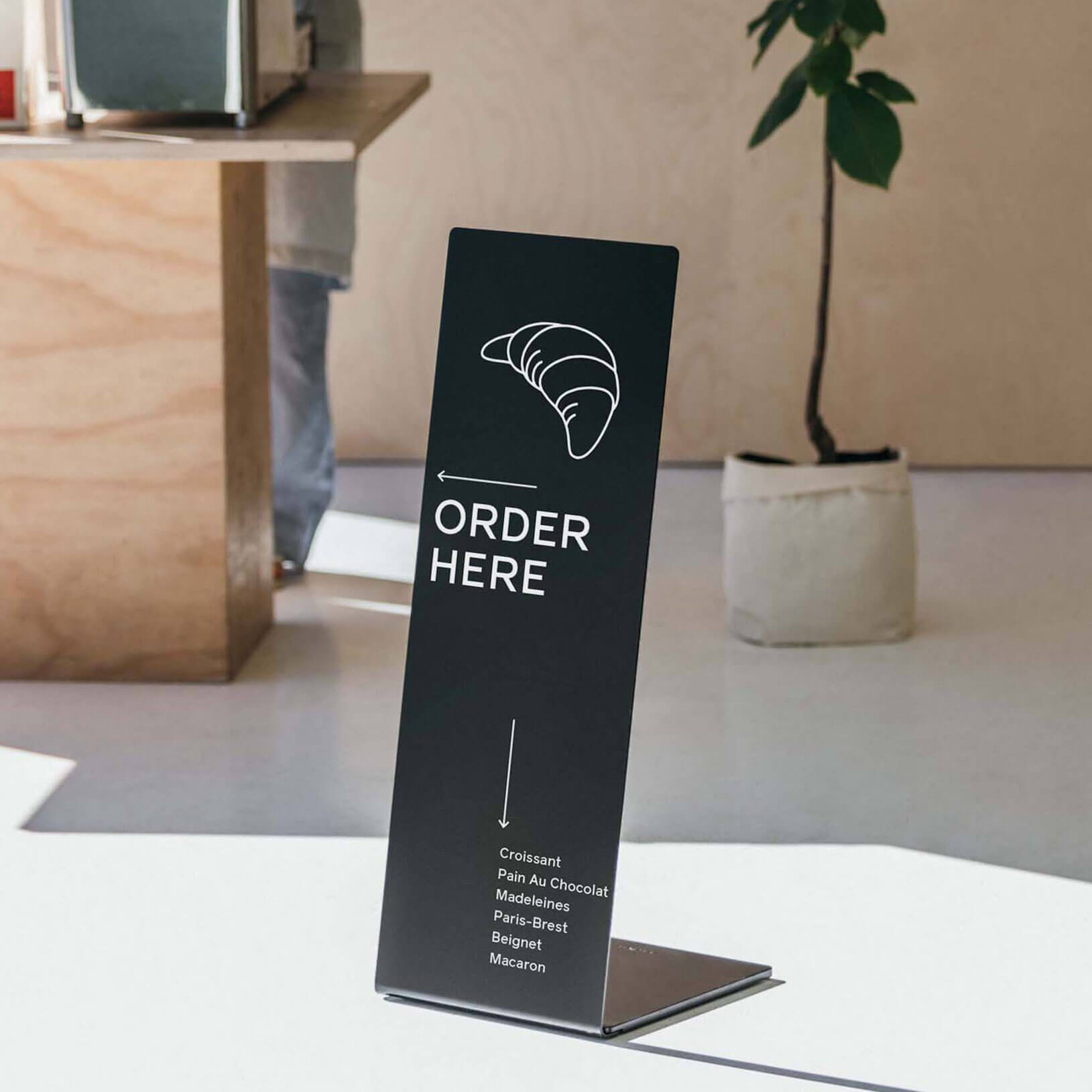 black metal freestanding sidewalk business sign in a courtyard