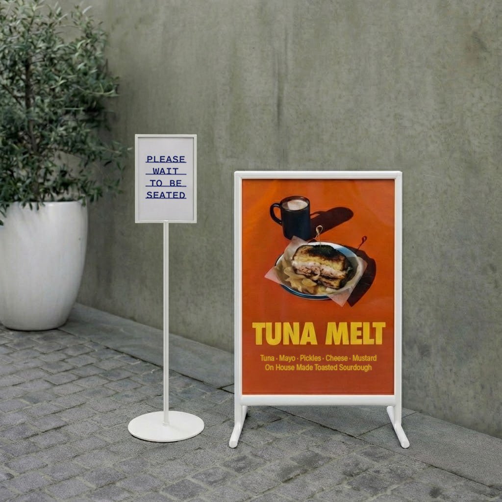 Outdoor seating sign with a tuna melt advertisement and a 'Please Wait to be Seated' sign.
