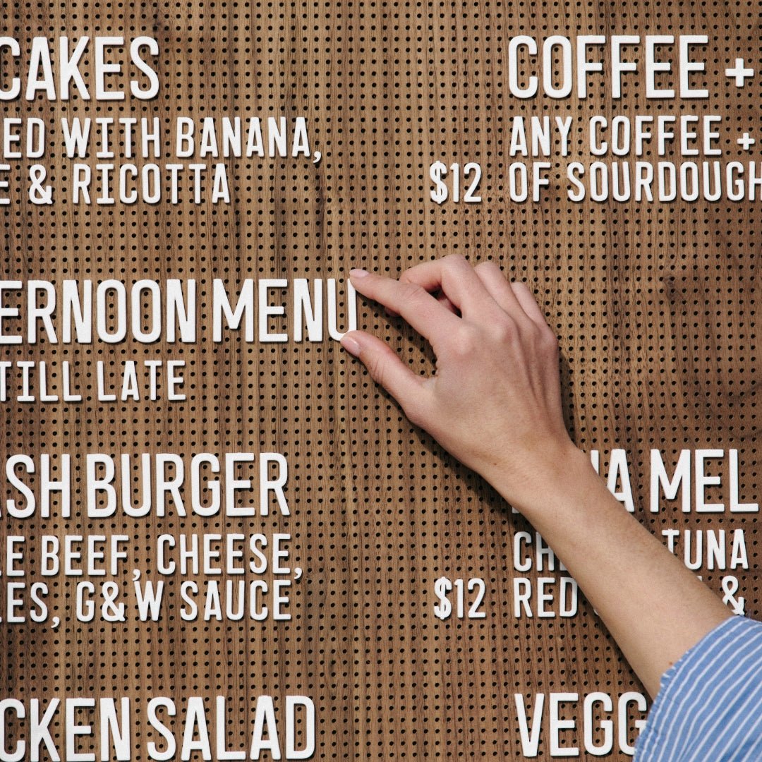 hand adjusting the white peg letter board letters on a wooden peg letter menu