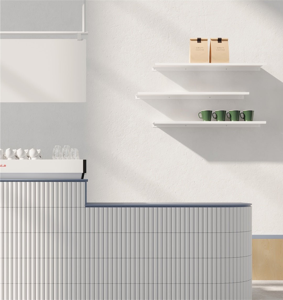three white floating industrial shelves installed above each other in a cafe behind a coffee shop counter