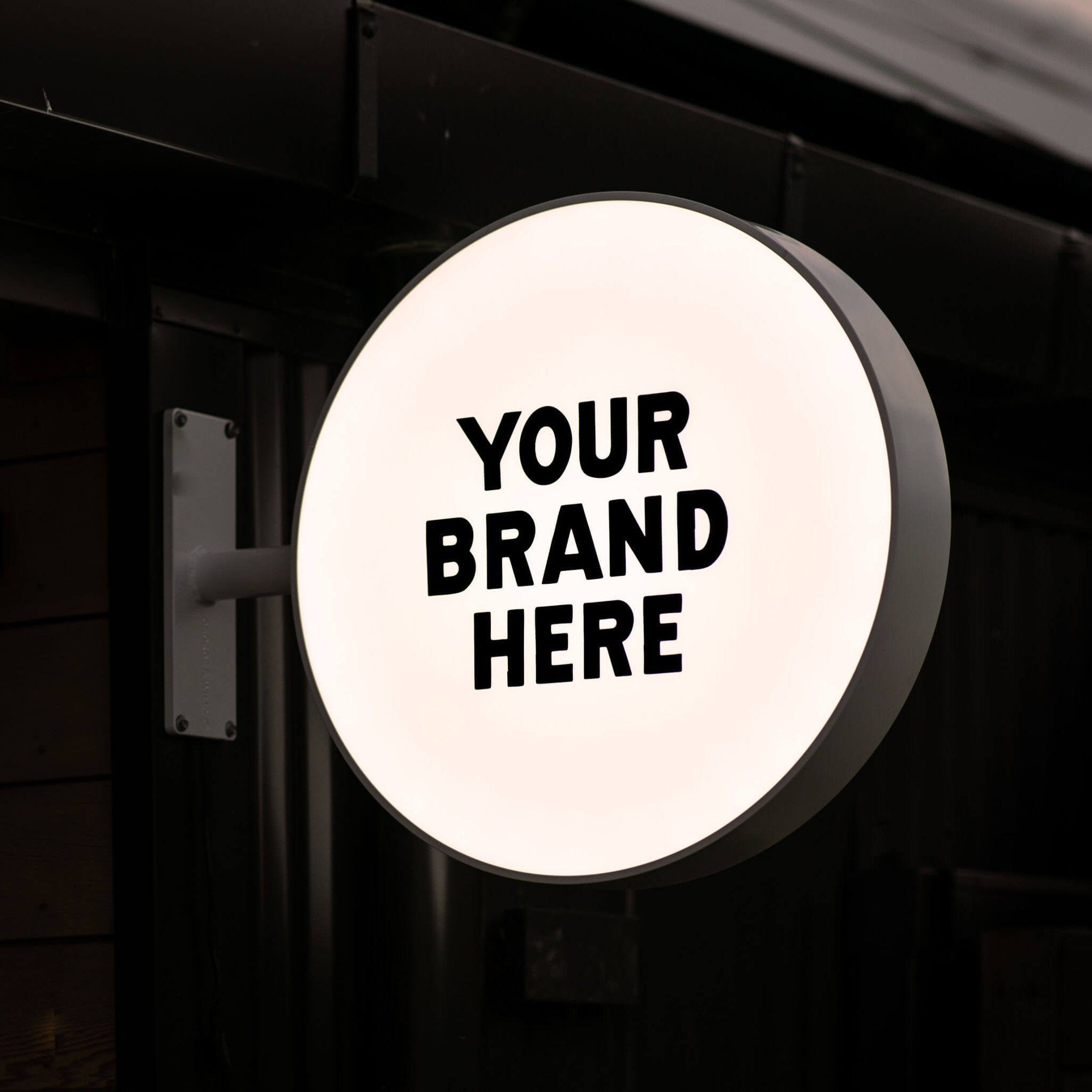 lit up round light box wall sign with "your brand here" displayed on the panel for an example logo