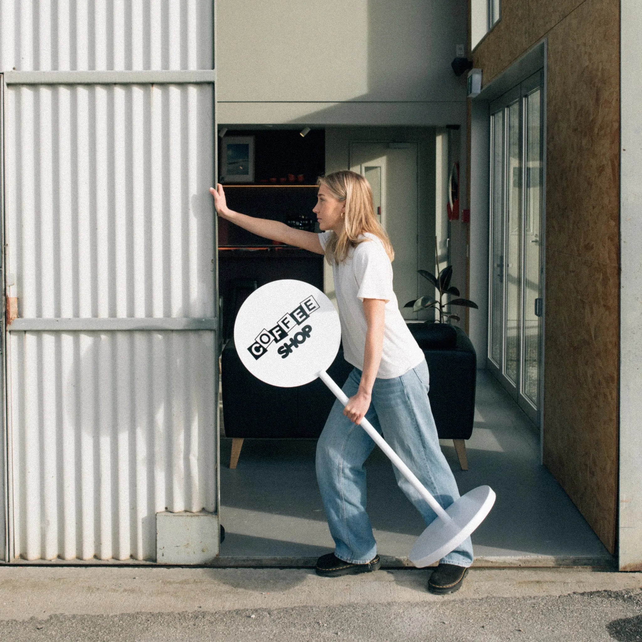 girl carrying a white free-standing lollipop sign while opening a door