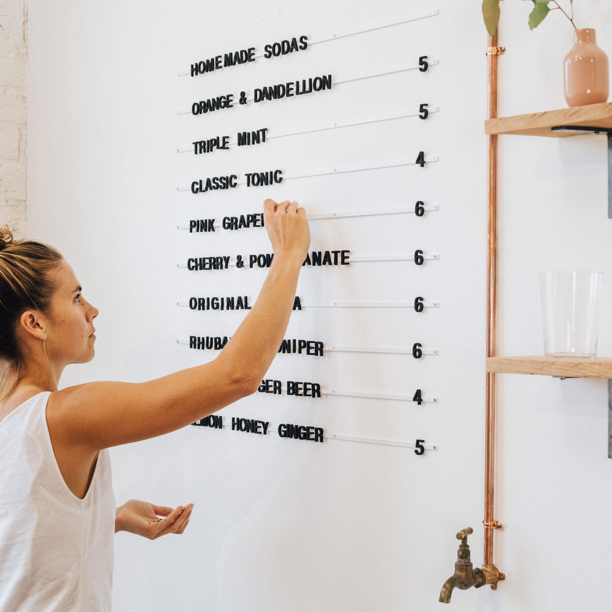 white magnetic menu board rails with black letters and girl standing in front changing the letters